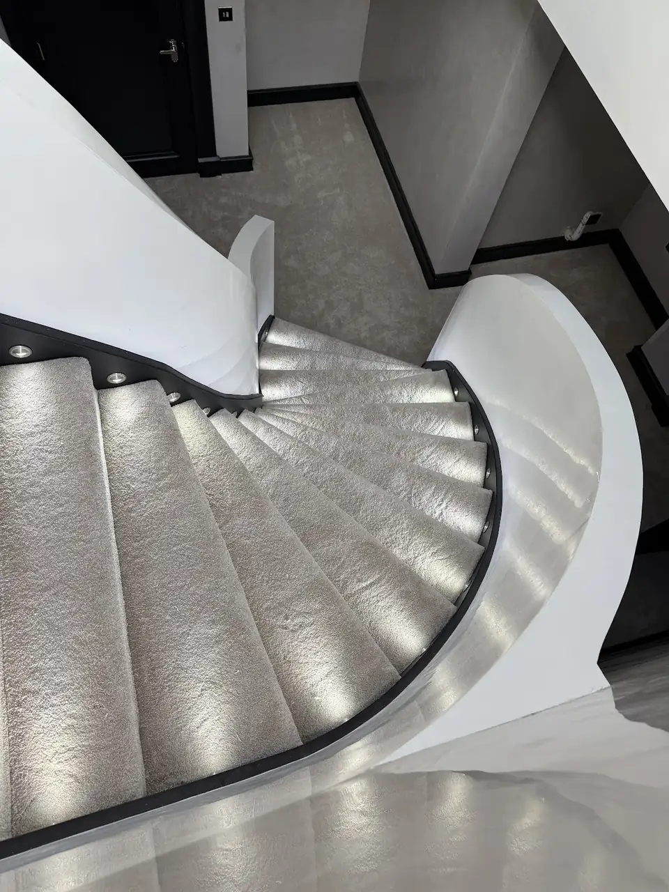 Grey carpet fitted on a curved staircase with step lights, by Scott The Carpet in Horsham