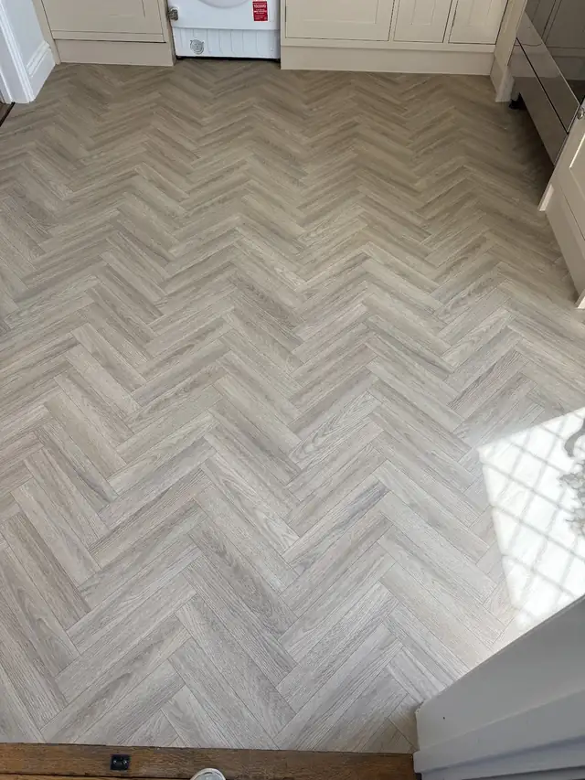 Light grey herringbone wood-effect floor in a kitchen