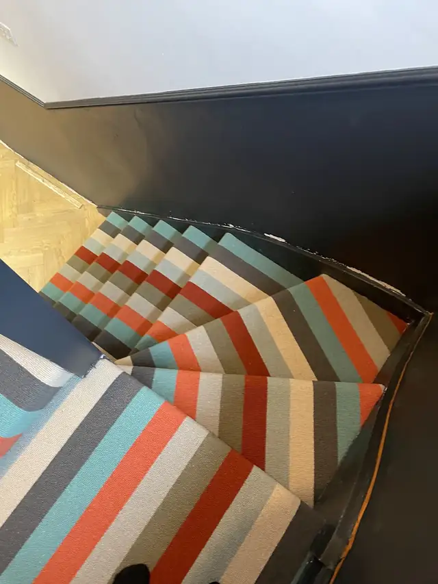 Striped multicoloured carpet fitted on a winding staircase